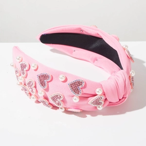 Detail of pink knotted headband featuring rhinestone heart charms and white pearls