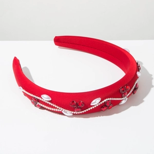 Détail macro du serre-tête en velours rouge avec cristaux trèfle et perles pour coiffure