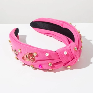 Détail d'un serre-tête noué rose avec perles, strass et breloque cœur LOVE