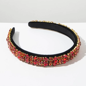 Close-up of luxury baroque headband with red rhinestones and gold claws on black velvet