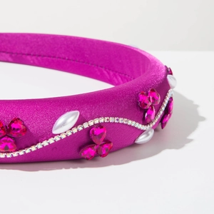 Détail du serre-tête en satin fuchsia avec strass roses, perles et chaîne de cristal