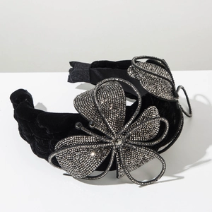 Macro detail of rhinestone encrusted flower on a black velvet headband with vintage style