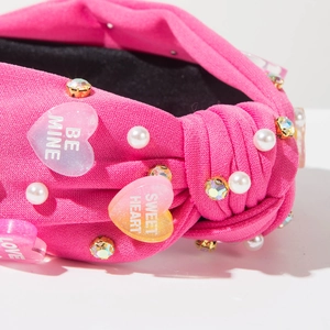 Detail of pink knotted headband with pearls, rhinestones, and Love heart charms