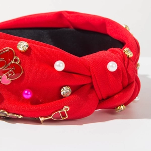 Gros plan du serre-tête rouge avec perles, strass et pendentifs LOVE en cœur