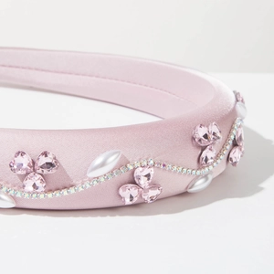 Détail d'un serre-tête rose avec strass en cœur, perles et chaînes de cristaux ondulées