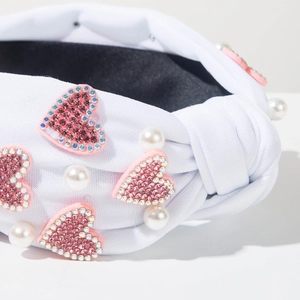 Close-up of white knotted headband featuring pink rhinestone hearts and white faux pearls