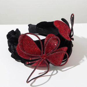 Detailed close-up of velvet headband with handmade red rhinestone butterfly accents