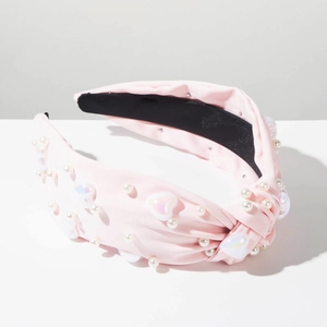 Détail du bandeau rose noué avec perles blanches et ornements en forme de cœur irisé