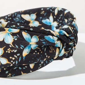 Détail d'un serre-tête noué bohème avec imprimés papillons bleus sur tissu noir