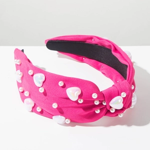 Détail du serre-tête en tissu rose avec perles blanches et perles en forme de coeur