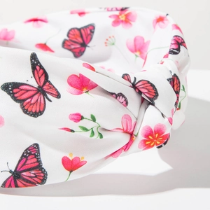 Détail d'un bandeau bohème à nœud avec imprimé papillon rose et fleurs sur tissu blanc