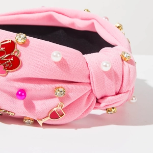 Détail d'un serre-tête noué rose avec perles, strass et breloques cœur LOVE