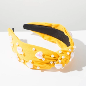 Détail d'un serre-tête en tissu jaune avec perles blanches et perles en forme de cœur