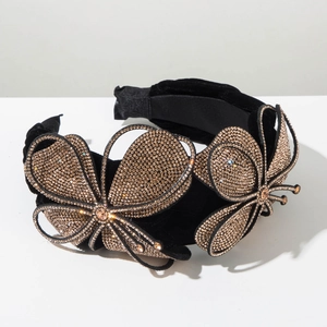 Detail of a wide black velvet headband featuring a large gold crystal butterfly design