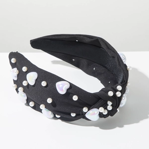 Détail d'un serre-tête noir torsadé orné de perles blanches et de charms de cœur nacrés