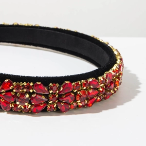 Detail shot of red teardrop crystals on luxurious black velvet headband with gold claw settings