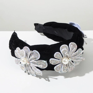 Détail de fleurs argentées avec perles et strass sur un serre-tête en velours noir