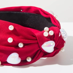 Gros plan sur serre-tête rouge avec perles élégantes et cœurs en acrylique irisé