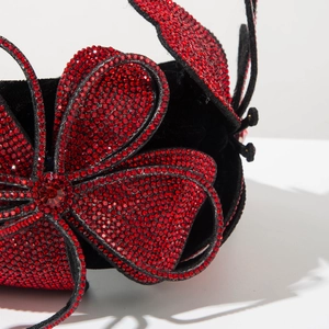 Detailed macro view of handcrafted red rhinestones on a black velvet butterfly headband