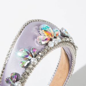 Dettaglio macro della fascia in raso lilla con strass scintillanti e perle decorative