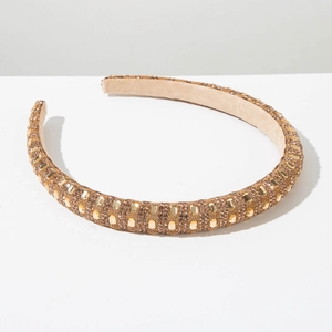 Macro detail of padded gold headband with dense rhinestone and bead embellishments