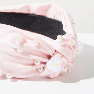 Gros plan du serre-tête en tissu rose avec perles blanches et perles en cœur
