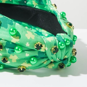 Macro detail of St. Patrick's Day headband with green shamrocks, pearls and emerald gems
