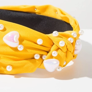 Détail d'un serre-tête noué jaune avec perles incrustées et cœurs irisés