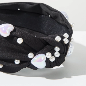 Détail du serre-tête en tissu noir avec perles et cœurs en résine sur nœud torsadé