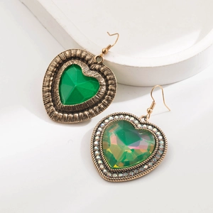 Détail de boucles d'oreilles cœur vert asymétriques avec accents dorés et cristaux