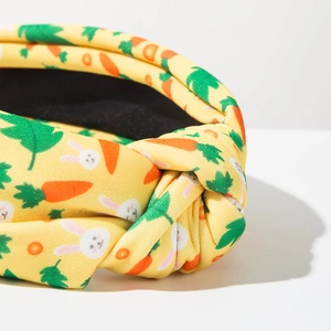 Detailed close-up of yellow fabric headband featuring bunny and carrot prints with top knot