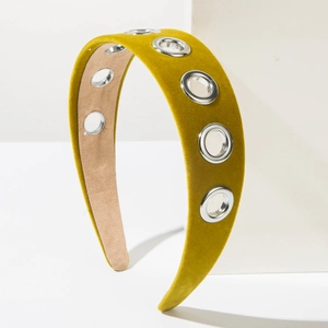 Detailed close-up of mustard yellow velvet headband with silver metal eyelets accents