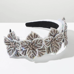 Close-up of elegant baroque white headband with five rhinestone flowers and grey crystals