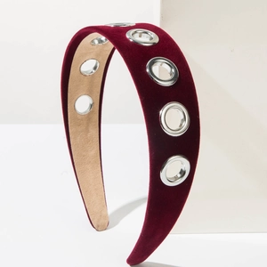 Close-up of burgundy velvet headband with silver metal eyelets on a geometric stand