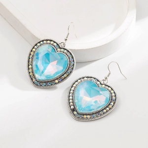 Gros plan de boucles d'oreilles cœur vintage avec cristal bleu et strass arc-en-ciel