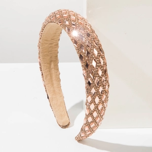 Chic rose gold wide headband covered in shimmering rhinestones on a white podium
