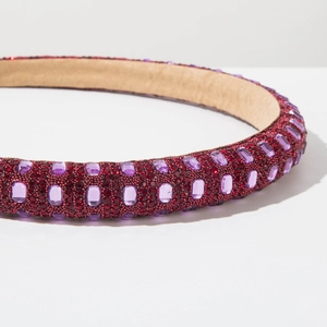 Macro detail of red rhinestone headband with purple crystals on a soft base