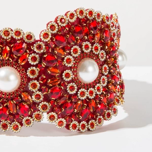 Macro d'un serre-tête baroque avec cristaux rouges et perles sur monture en métal doré
