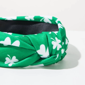 Close-up of green knotted headband with white shamrock pattern for St. Patrick's Day