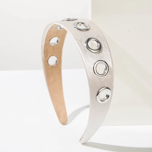 Detail of champagne satin headband with silver metal eyelets on a geometric stand