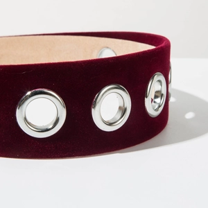 Detail of burgundy velvet headband with metallic eyelets and smooth inner lining texture