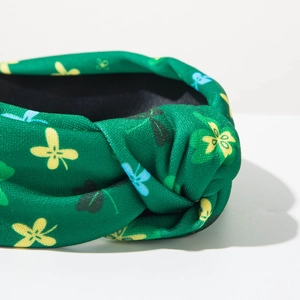 Close-up of green knotted headband with yellow and blue clover prints and fabric texture