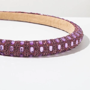 Macro shot of purple rhinestone headband showing luxury crystal setting and beige velvet lining