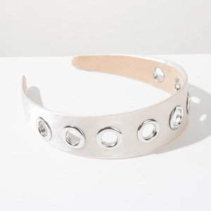 Detail of wide satin headband with silver metal eyelets and beige fabric texture
