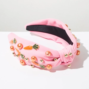 Detail van roze stoffen haarband met oranje parels en emaille wortelbedels