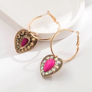 Detailed macro view of bohemian golden hoop earrings with pink turquoise heart pendant