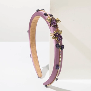 Detailed macro of vintage purple headband with gold bee accents and sparkling gemstones