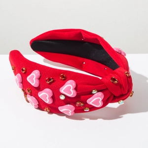 Detailweergave van rode geknoopte haarband met roze hartjes en fonkelende kristallen