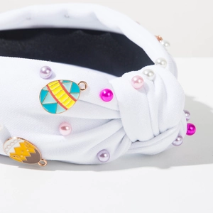 Detailed close-up of white knotted headband with colorful pearls and Easter egg charms