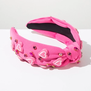 Detail van een felroze geknoopte haarband met hartdecoratie en gekleurde strass-stenen